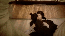 a woman is kissing a man on the cheek while laying on a bed .