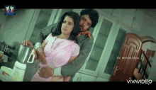 a man is holding a woman in his arms in a kitchen while she uses a blender .