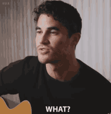 a man in a black shirt is holding a guitar and saying what