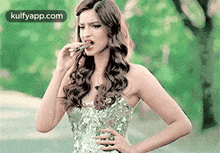 a woman in a silver dress is eating a piece of food .