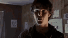 a young man is standing in a dark room with his mouth open and looking at the camera .