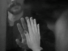 a black and white photo of a man and a woman touching each other 's hands