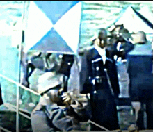 a man in a military uniform stands in front of a blue flag