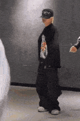 a man wearing a hat and a black shirt is standing in a room