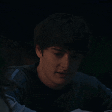 a young man in a dark room looks at the camera