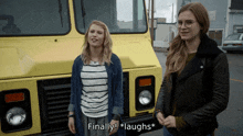 two women standing in front of a yellow truck with the words finally laughs