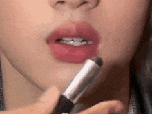 a close up of a woman applying lipstick to her lips with a brush .
