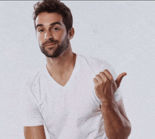 a man with a beard is wearing a white t-shirt and pointing