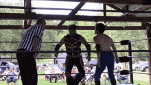 a referee and two wrestlers in a ring with a crowd watching