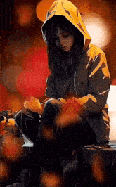 a girl in a hooded jacket is sitting in the rain holding a leaf .