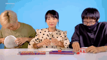 three people sitting at a table with a box that says manufactured in osaka on it