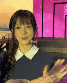 a girl with braided hair is holding someone 's hand in front of a pink background with the word bun on it