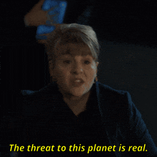 a woman in a dark room with the words the threat to this planet is real