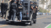a group of police officers are standing in front of a lenco truck