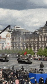 a crowd of people watching a military parade with a large building in the background that says ' cccp ' on it