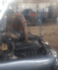 a blurry picture of a person sitting in a car with the hood open