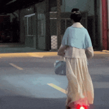 a woman in a blue jacket and white skirt is walking down the street