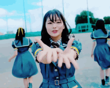a girl in a blue dress is making a peace sign with her hands