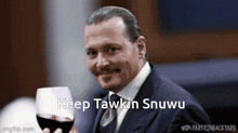 a man in a suit and tie is holding a glass of wine and says keep tawkin snuwu
