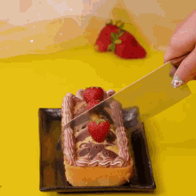 a person is cutting a chocolate cake with strawberries on top