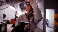 a woman with red hair is reading a book in a room with a red exit sign above her head