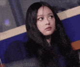 a young woman with long black hair is sitting in a chair looking at the camera .