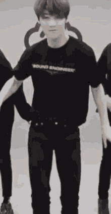 a man in a black shirt and black pants is dancing in a room with other people .
