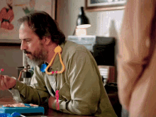 a man with a beard is sitting at a table with a toy stethoscope around his neck