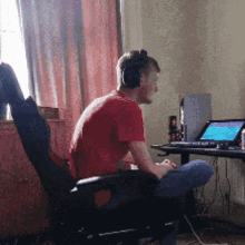a man wearing headphones sits in front of a laptop