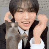 a man in a suit and tie is holding a cat in his hands