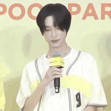 a man wearing a mask holds a microphone in front of a sign that says " pocopar "