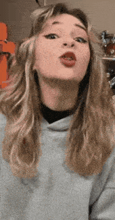 a girl with long blonde hair is making a funny face with her mouth open