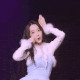 a woman in a blue dress and white fur coat is dancing on a stage .