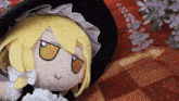 a stuffed doll with a yellow hair and a black hat