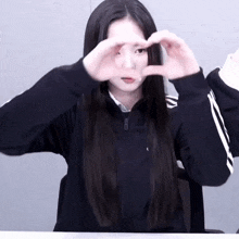 a girl making a heart with her hands in front of her face