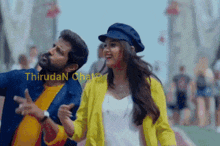 a man in a yellow jacket and a woman in a blue hat are dancing together