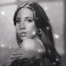 a black and white photo of a woman wearing hoop earrings and a fur coat