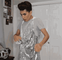 a man wearing a silver sequined dress is standing in front of a sony boombox
