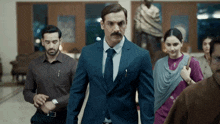a man in a suit and tie is walking in a room