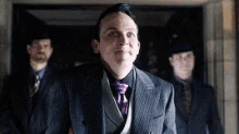 a man in a suit and tie is standing in front of two men in suits .
