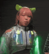 a woman with pink hair is wearing a silver jacket and a green headband
