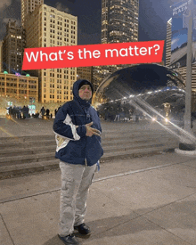 a man in a hooded jacket stands in front of a sign that says what 's the matter
