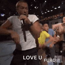 a man is singing into a microphone in front of a crowd and says love u furd