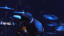 a man singing into a microphone in front of drums