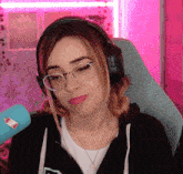 a woman wearing headphones and glasses has a sticker on her shirt that says ' coca-cola '