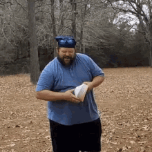 a man with a beard wearing a graduation cap is holding a book in a field .