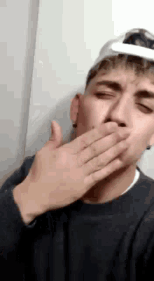 a young man is covering his mouth with his hand .