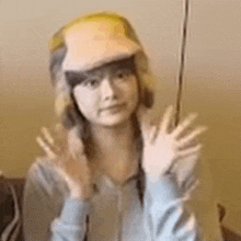 a woman wearing a hat and gloves is waving her hand .