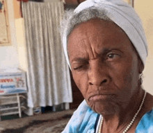 an elderly woman wearing a turban and pearls is making a funny face .