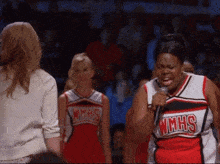 a cheerleader wearing a wmhs jersey holds a microphone